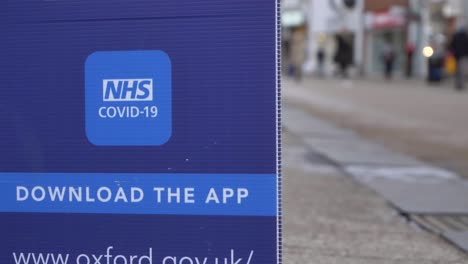 Handheld-Close-Up-Shot-of-COVID-NHS-Application-Signage-In-City-Centre-